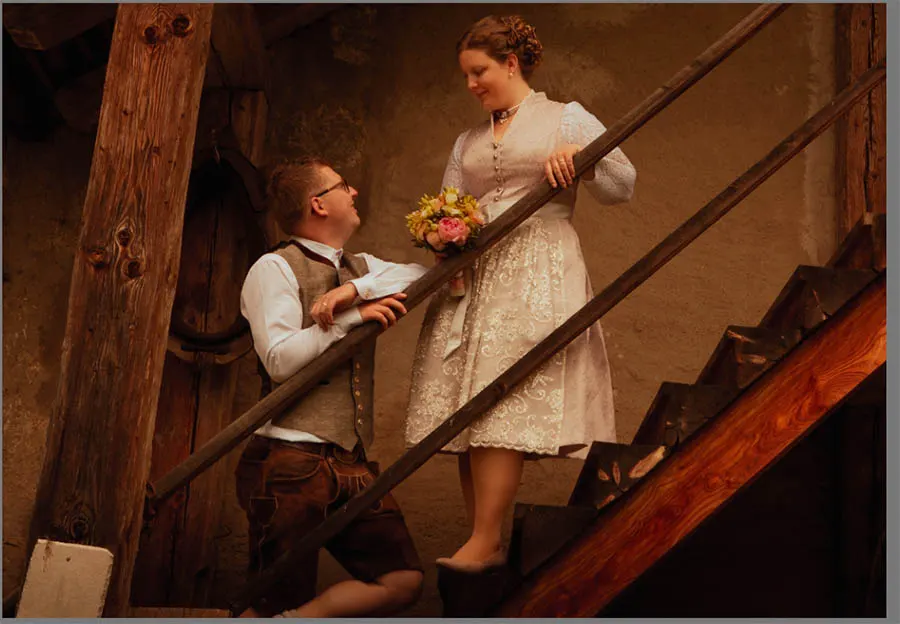 Ein Brautpaar steht auf einer Treppe, die Braut oberhalb und der Bräutigam auf einer unteren Stufe.